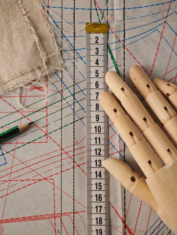 Flat lay of sewing patterns, a wooden hand, and measuring tape, perfect for tailoring themes.