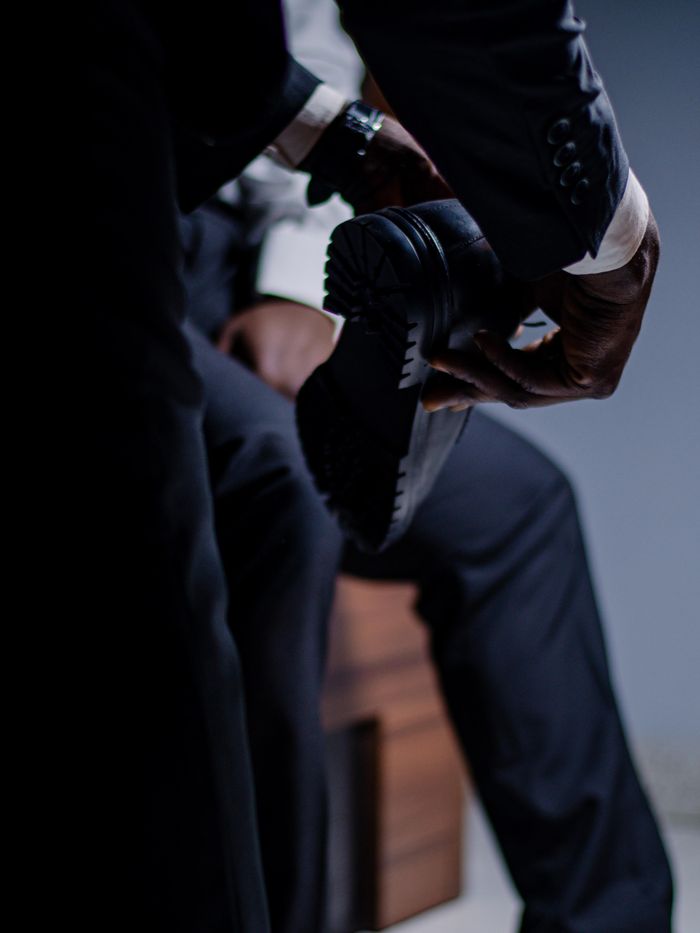 A close-up of a businessman in a sleek suit polishing his shoes, emphasizing elegance and professionalism.
